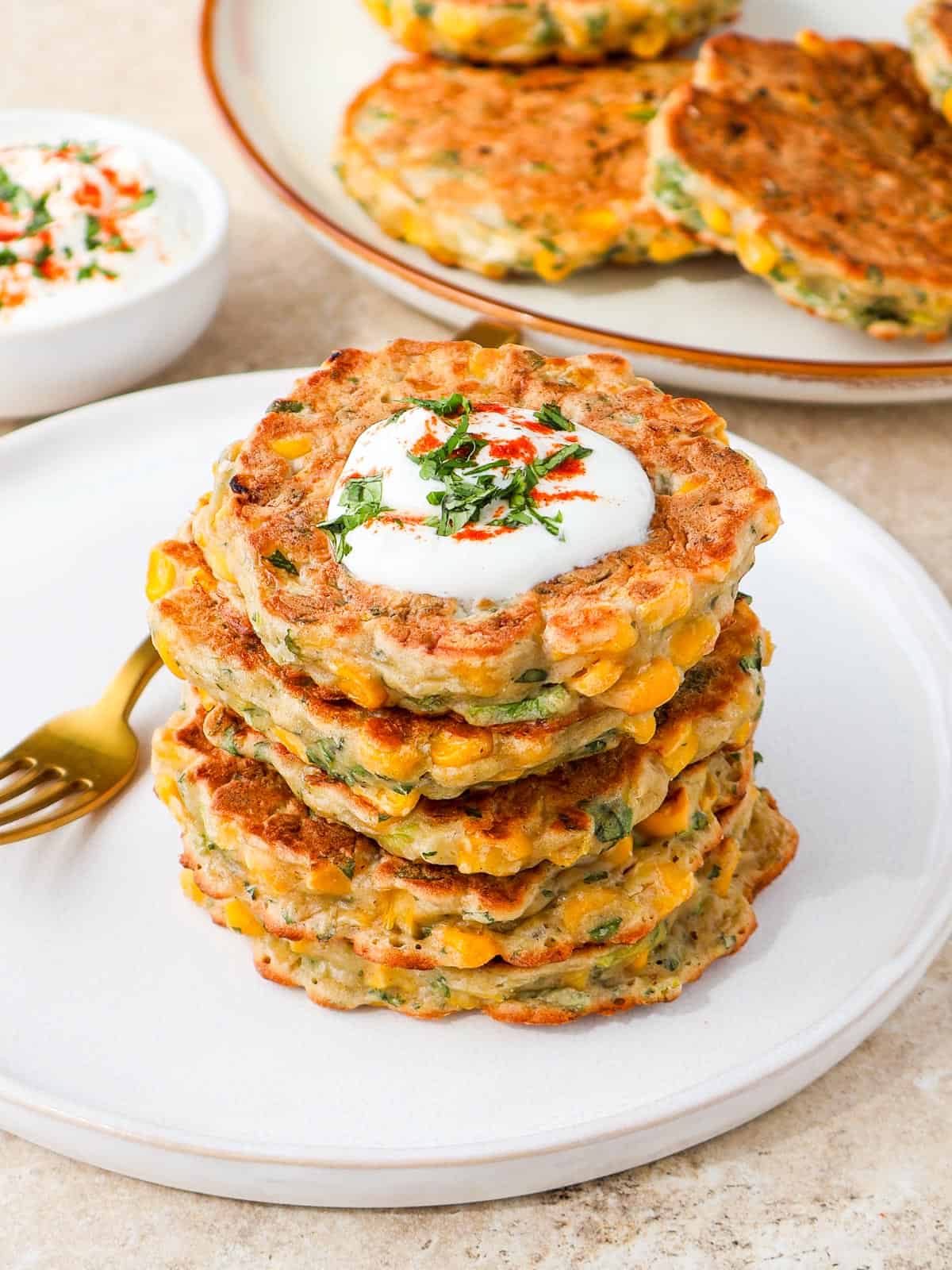 Side shot of corn fritters stacked on a plate.
