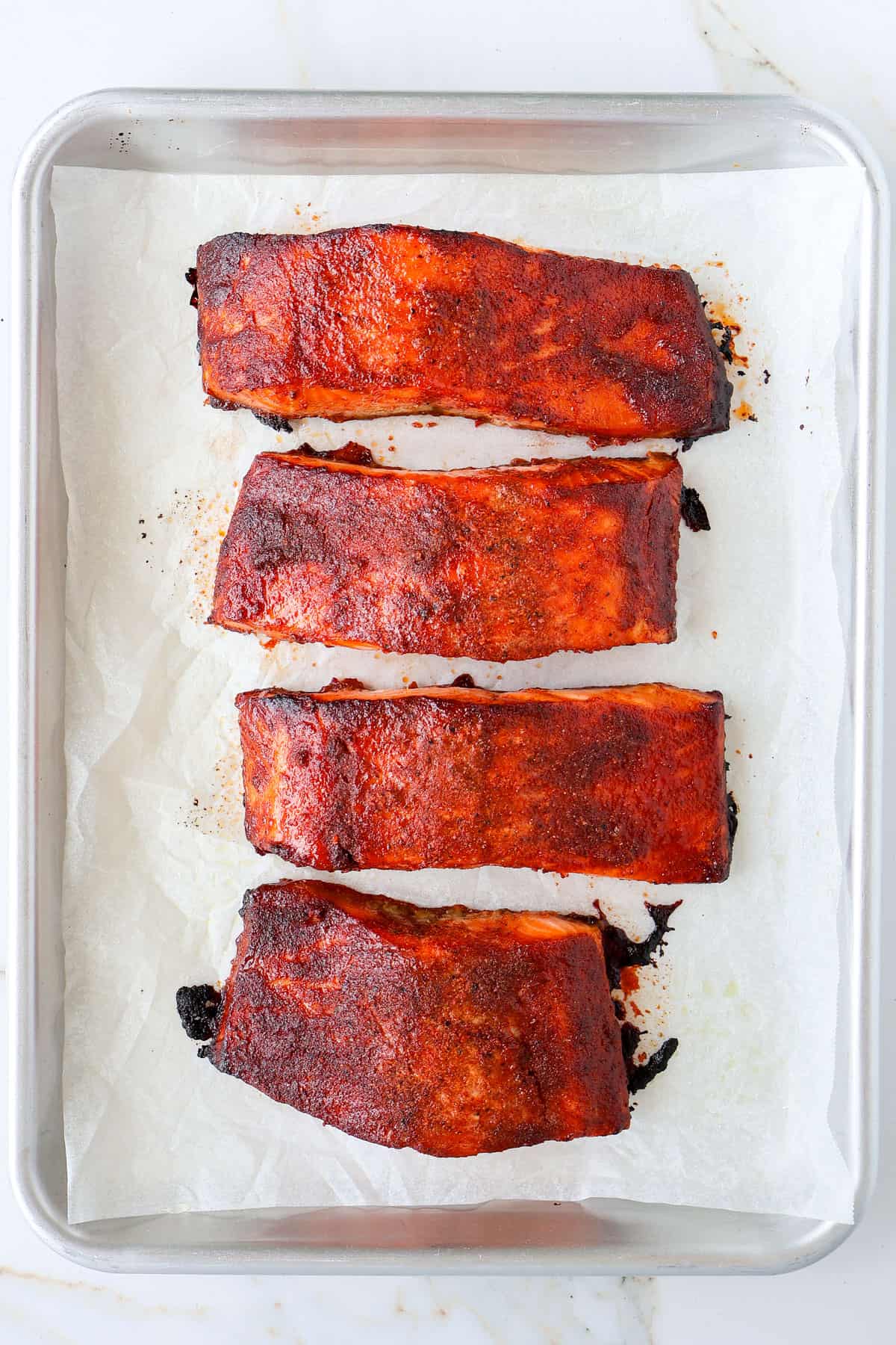 Grilled honey paprika salmon filets on a baking sheet.