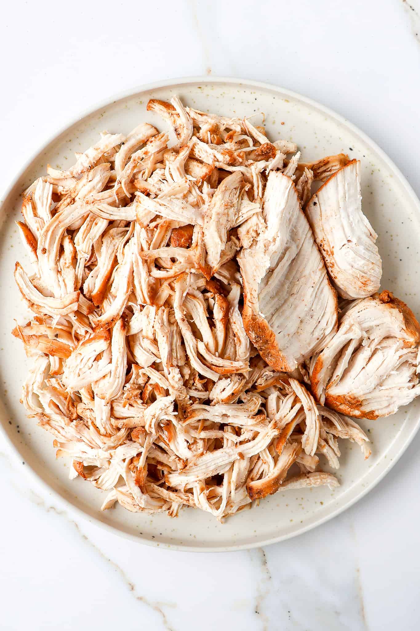 Chicken being shredded on a plate.