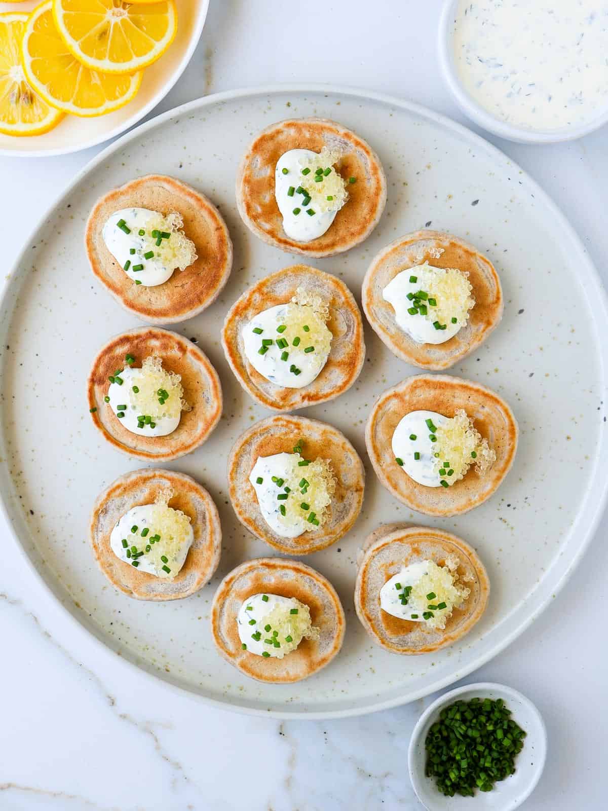 Blinis topped with the herb cream, caviar and chives. Lemon slices, chives and cream on the side.