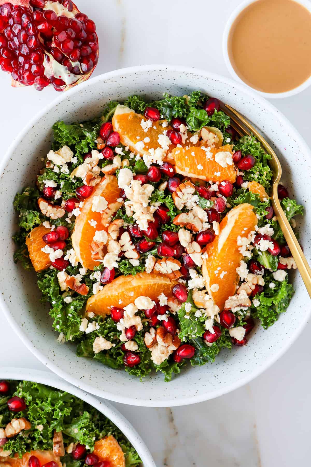 Pomegranate salad in a bowl with a gold fork.
