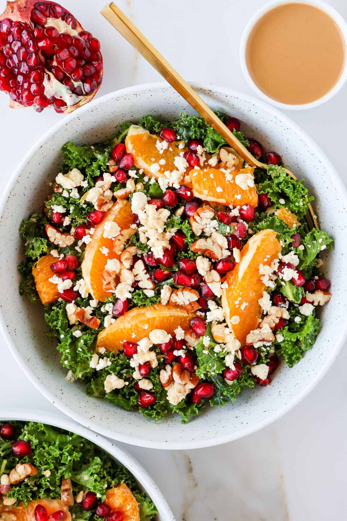 Kale and pomegranate salad in a bowl with a gold fork.