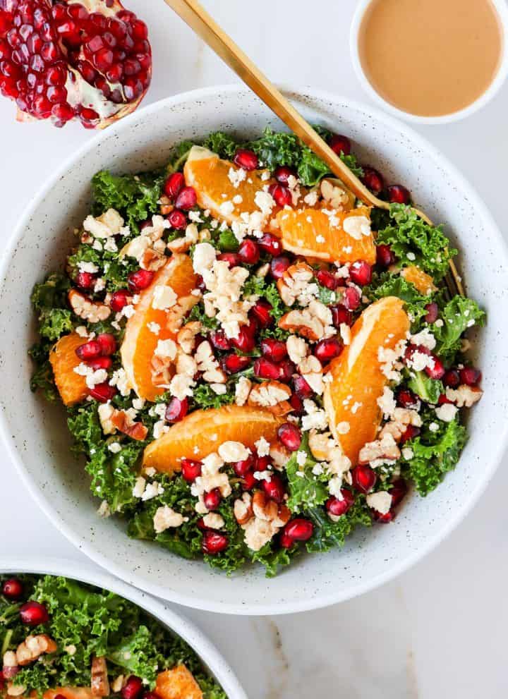 Kale and pomegranate salad in a bowl with a gold fork.
