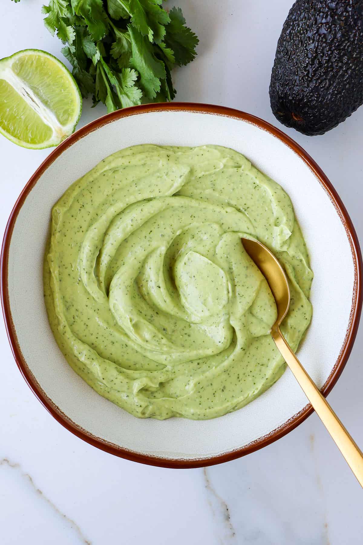 Avocado lime crema in a bowl with a spoon.