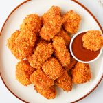 Cornflake chicken nuggets dipped into bbq sauce.