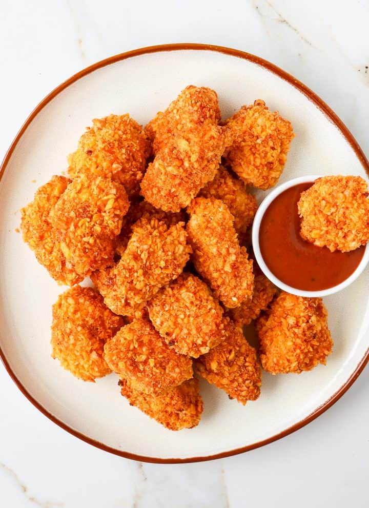 Cornflake chicken nuggets dipped into bbq sauce.