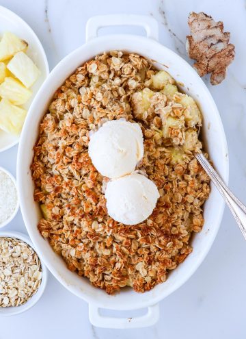 Pineapple crisp with a spoon topped with ice cream.