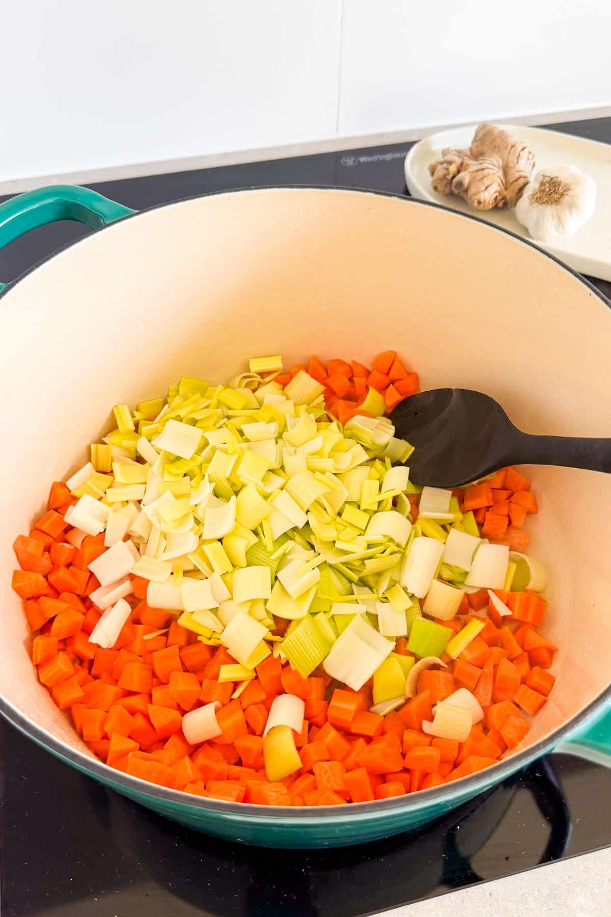 Carrots and leeks being sautéed in a pot.