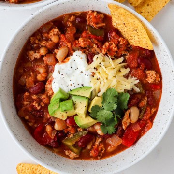 Ground chicken chili in a bowl with tortilla chips.