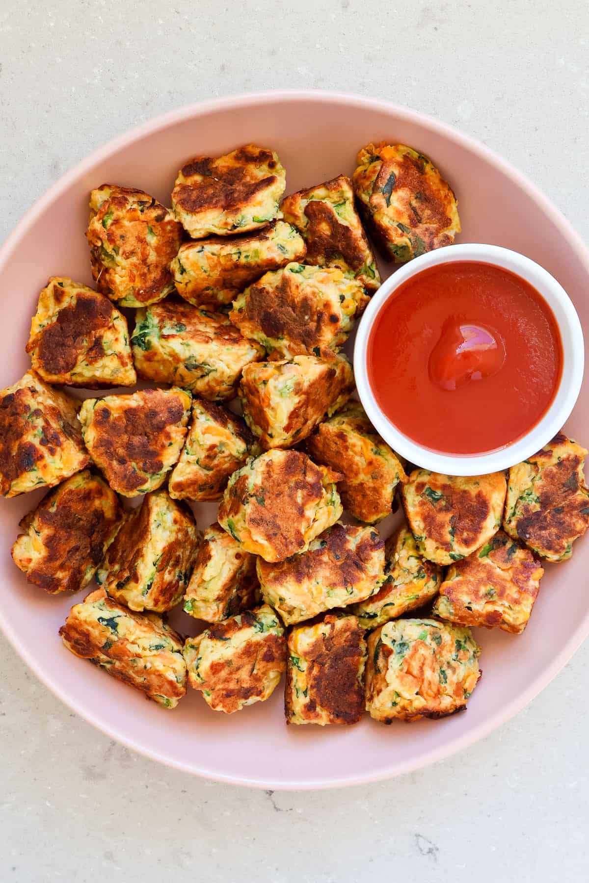 Ricotta fritters in a bowl with ketchup.