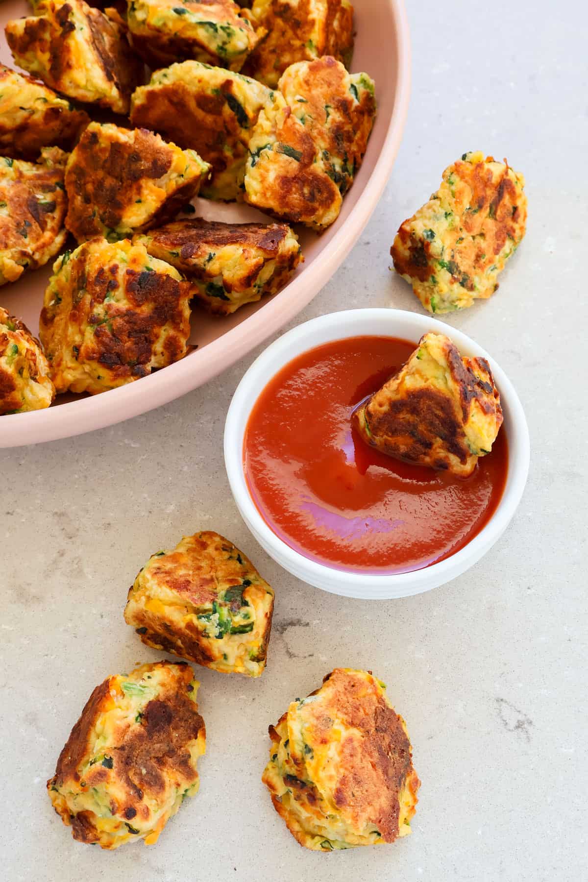Side shot of fritters being dipping in ketchup.