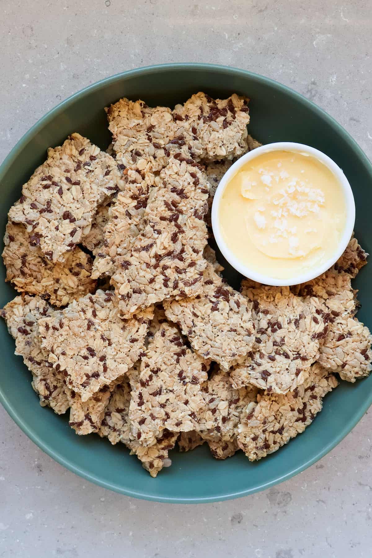 Oatmeal sunflower seed crackers in a bowl with salted butter.