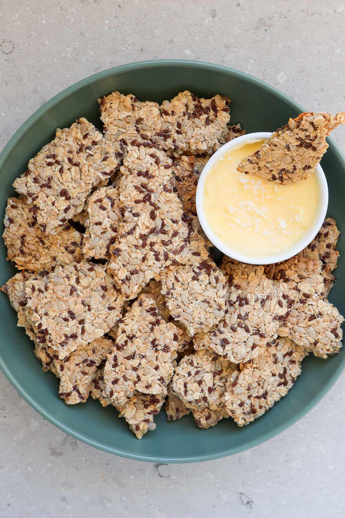 Oatmeal sunflower seed crackers in a bowl with salted butter in a dish.