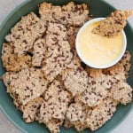 Oatmeal sunflower seed crackers in a bowl with salted butter in a dish.