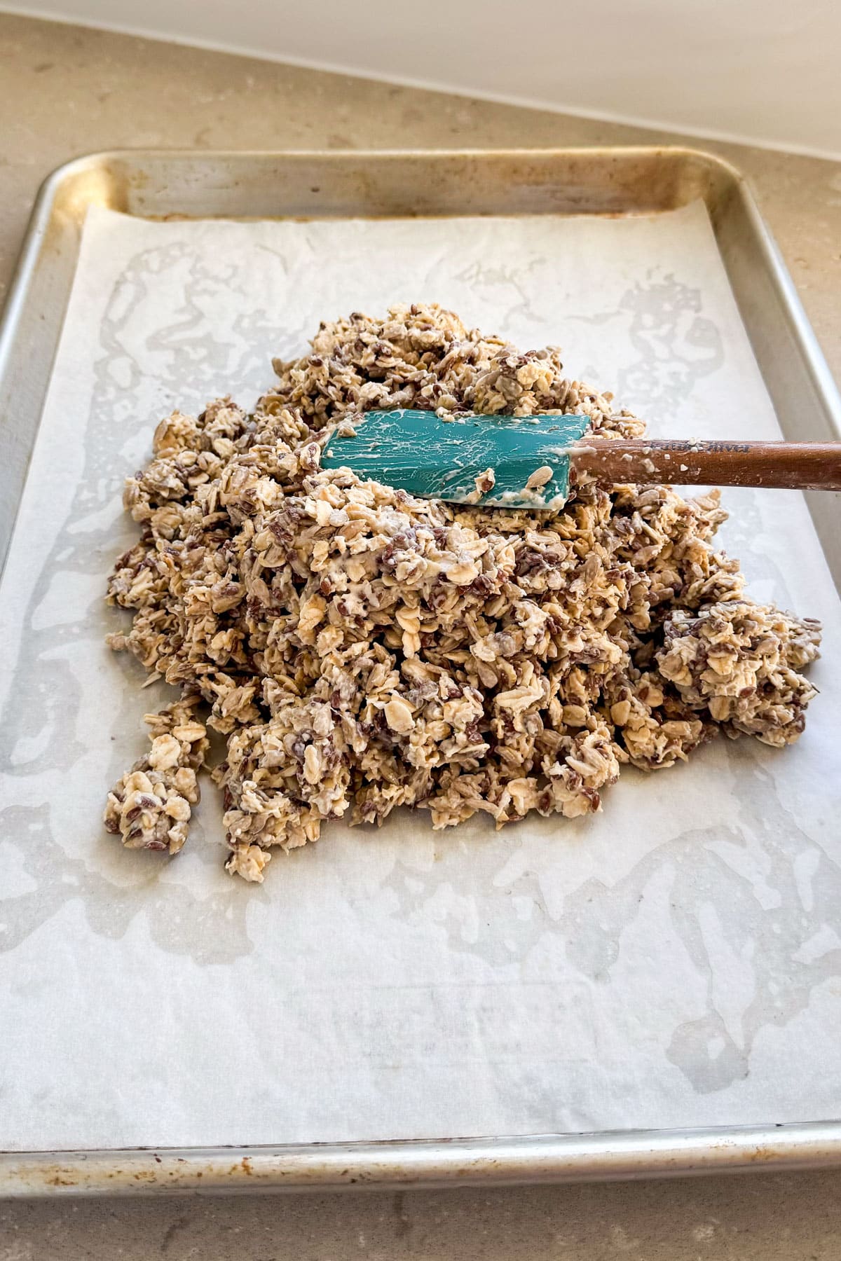 Seed mixture spread on baking tray with spatula.
