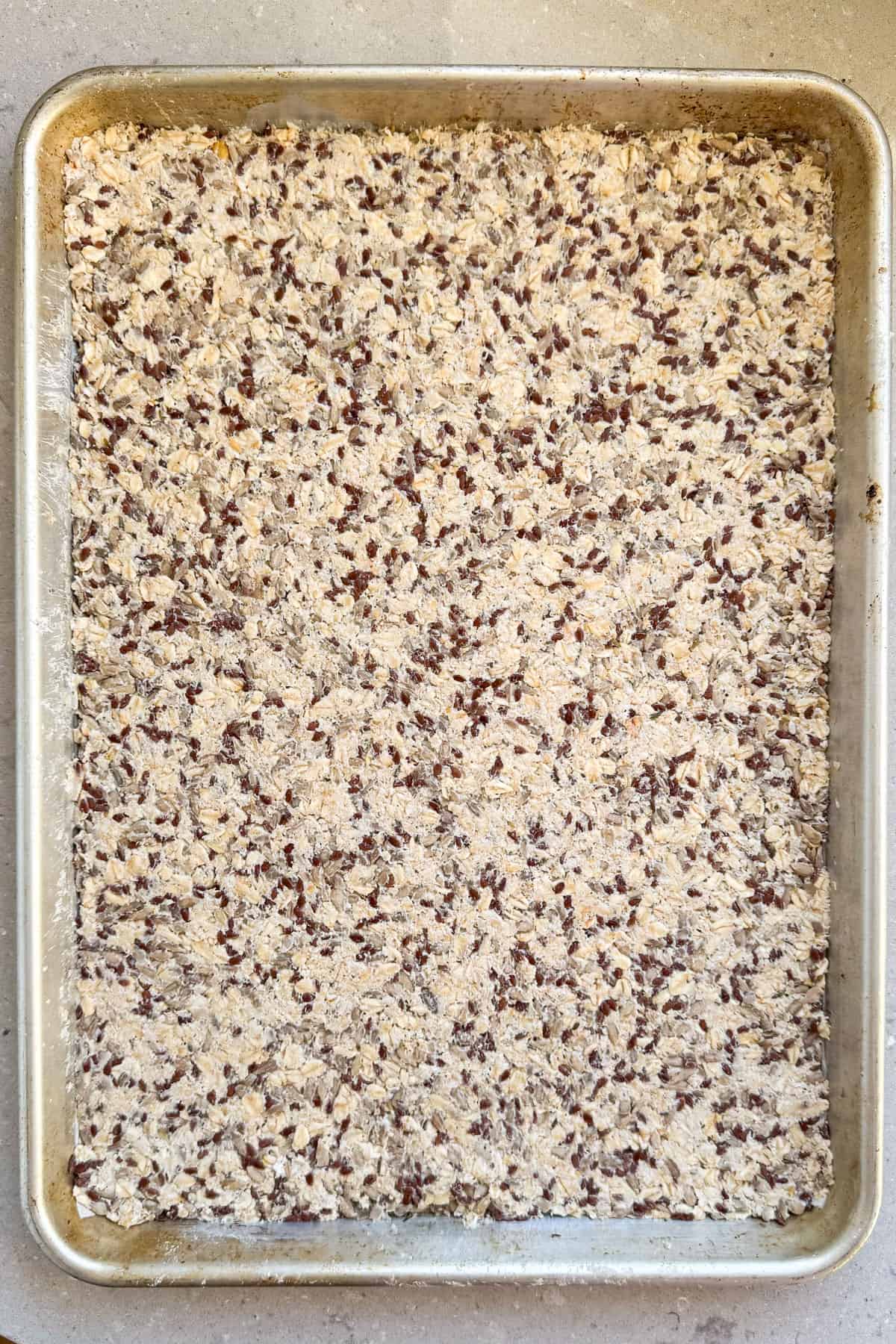 Seed mixture spread on baking tray in even flat layer.