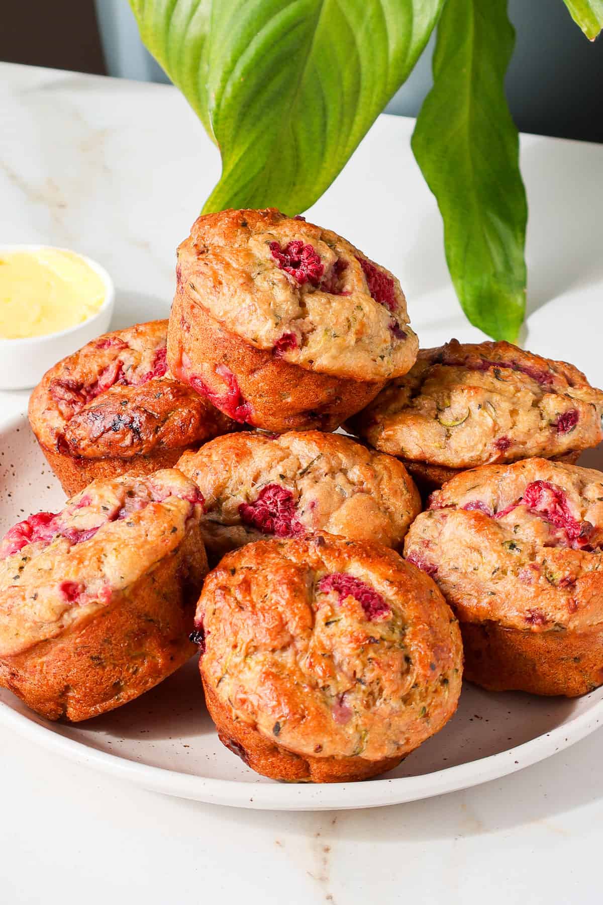 Side shot of banana raspberry muffins on a plate.