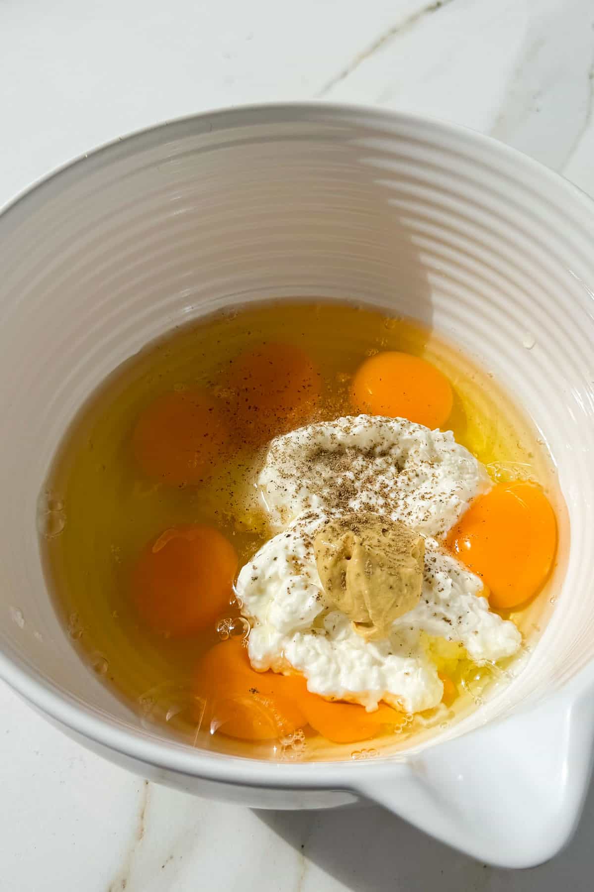 Eggs, cottage cheese and mustard added to a bowl.