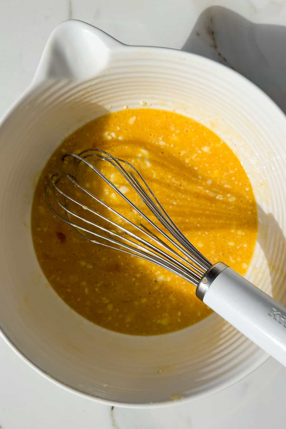 Eggs and cottage cheese being whisked in a bowl.