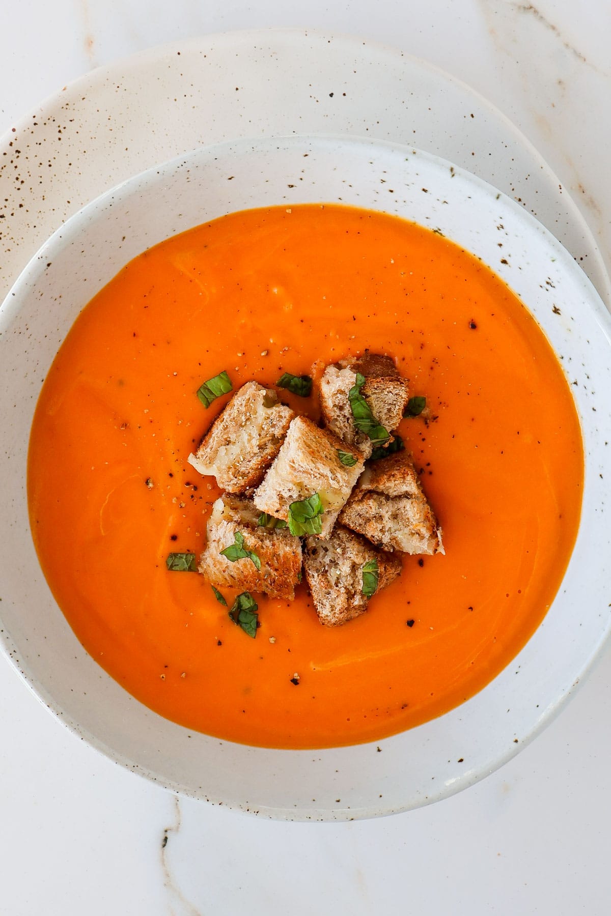 Butternut squash tomato soup in a bowl with grilled cheese.