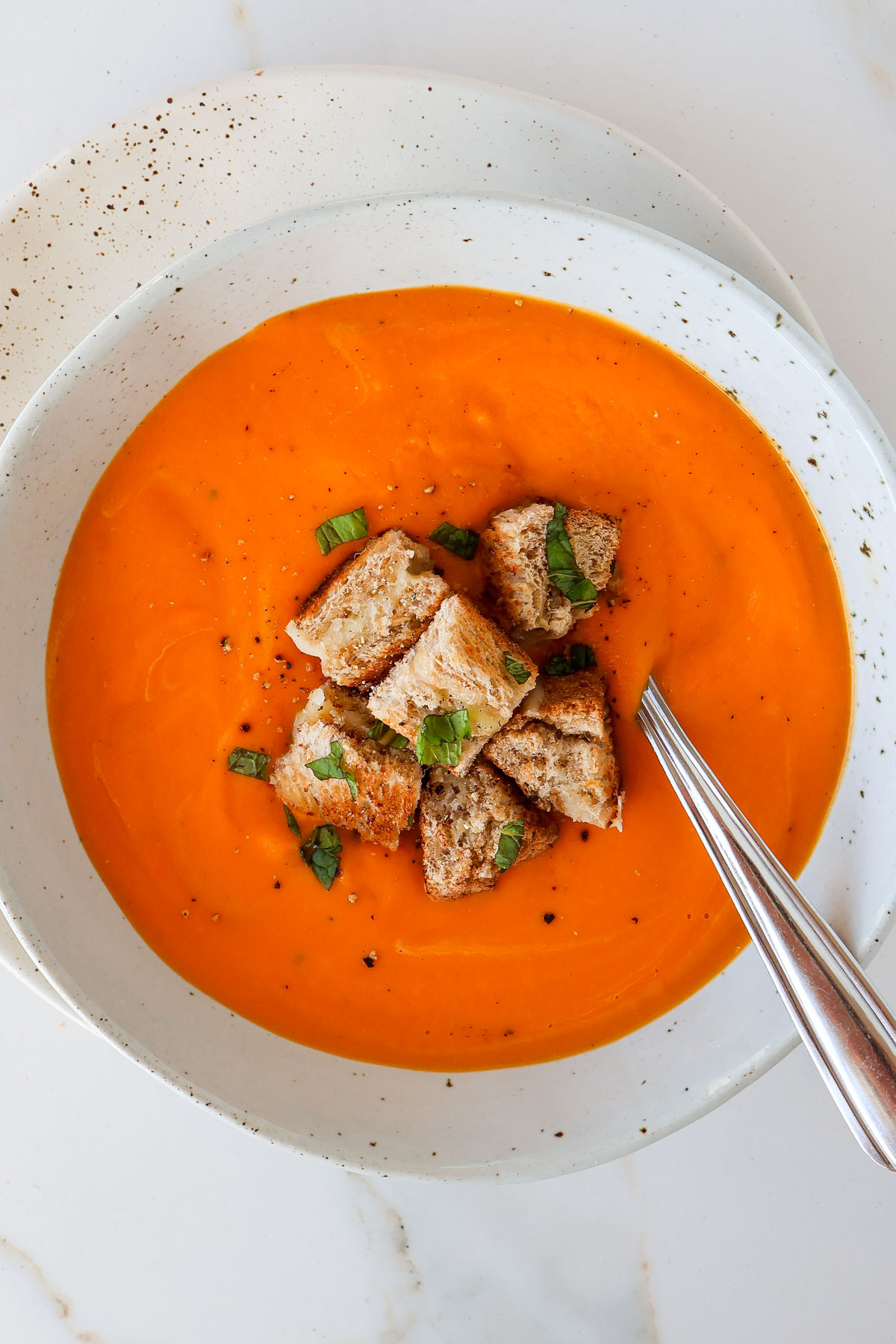Tomato butternut squash soup in a bowl with a spoon.