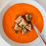 Tomato butternut squash soup in a bowl with a spoon.
