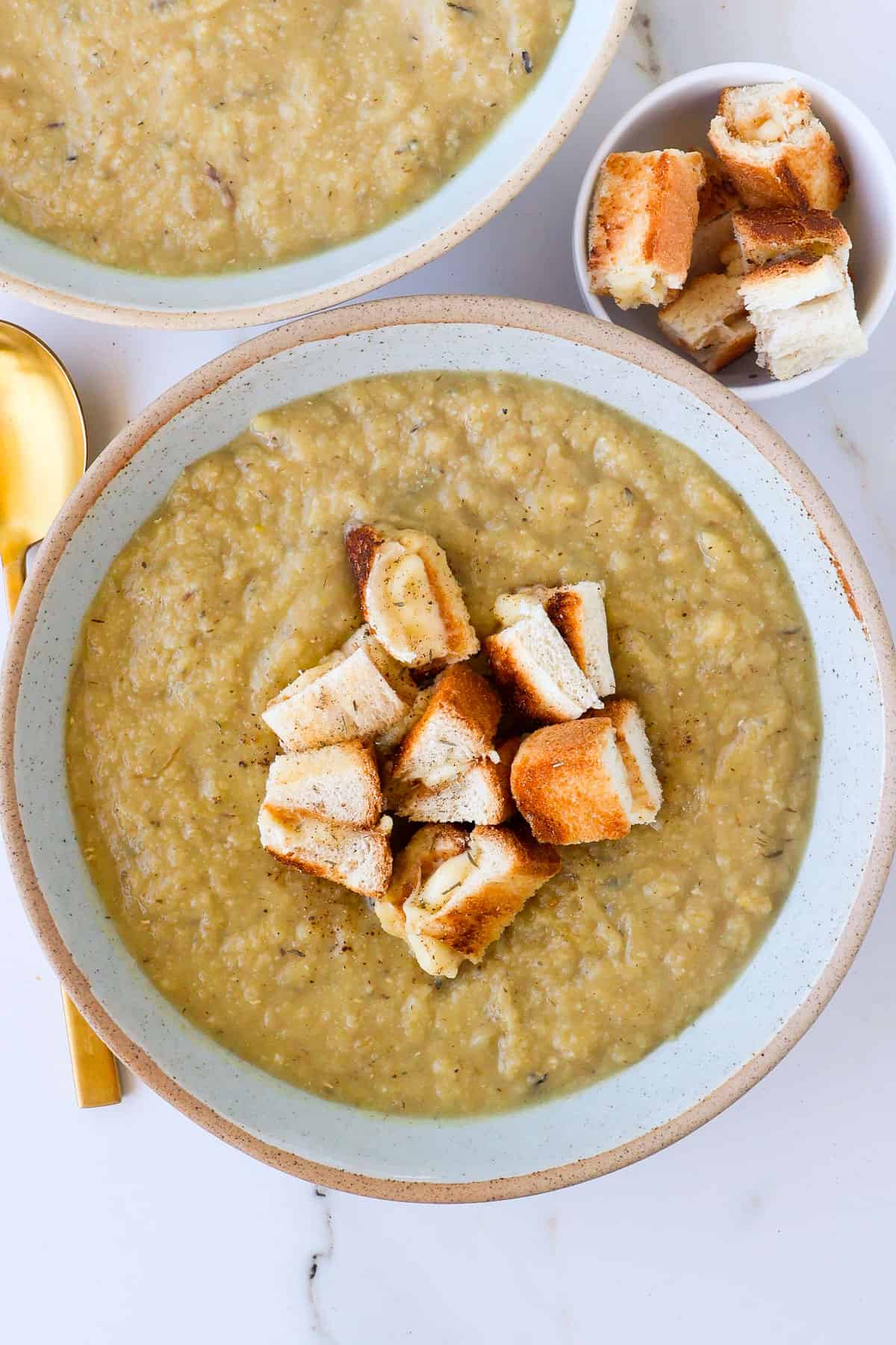 Cauliflower potato leek soup in a bowl with cut up grilled cheese toastie.