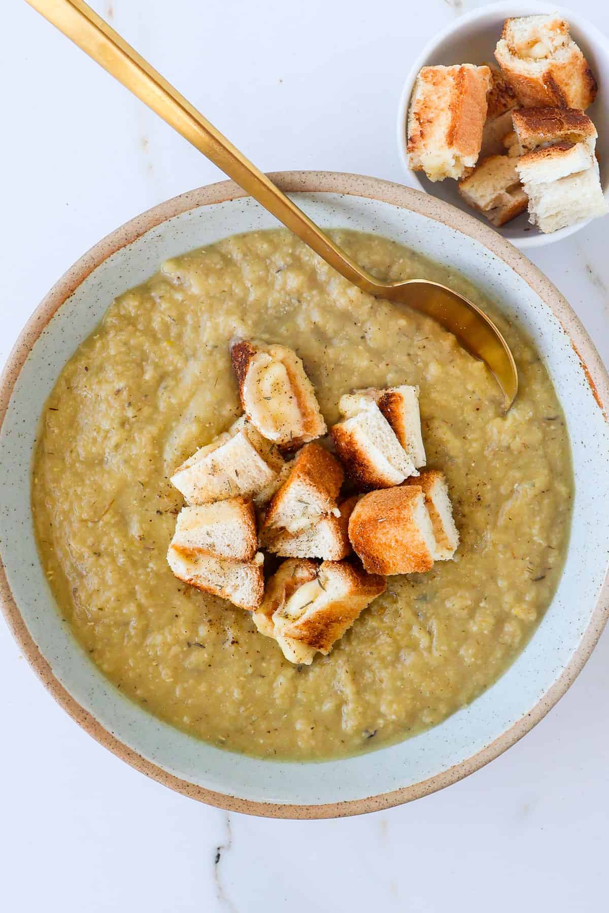 Cauliflower and potato soup in a bowl with a spoon.