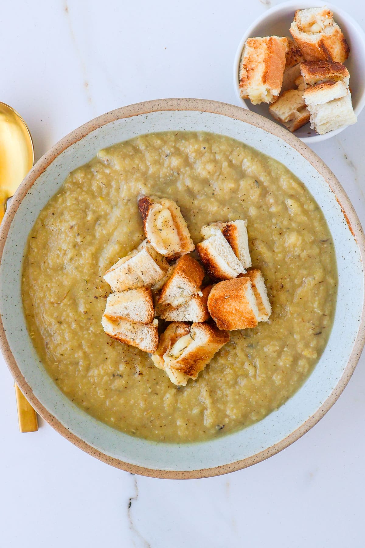 Cauliflower potato leek soup in a bowl with cut up grilled cheese toastie.