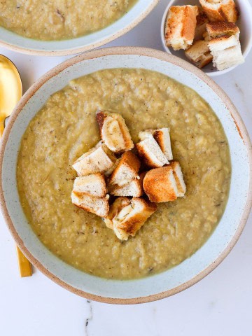 Cauliflower potato leek soup in a bowl with cut up grilled cheese toastie.