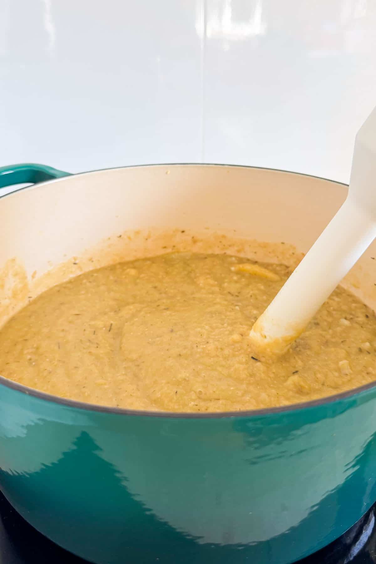 Soup being blended in the pot with an immersion blender.