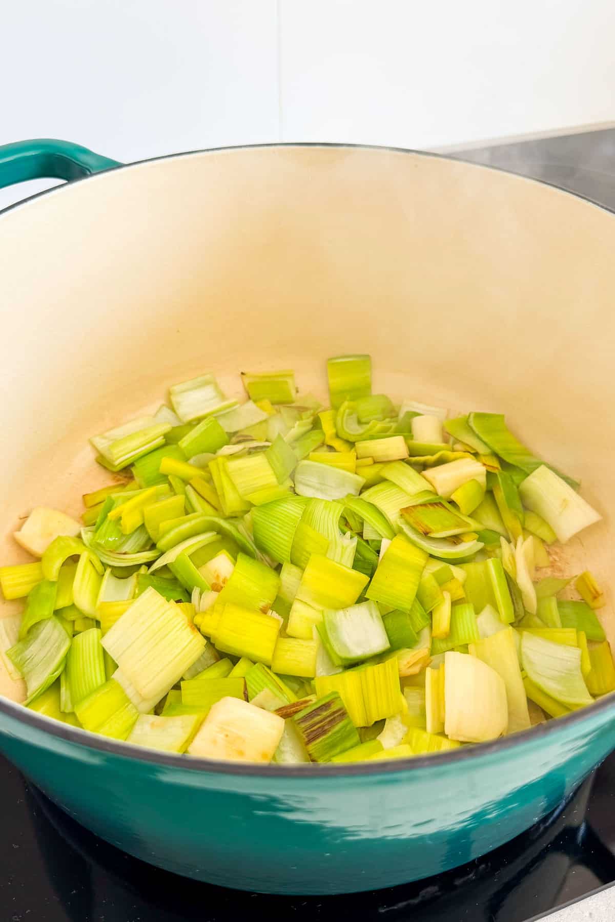 Leeks being sautéed in a pot with butter.