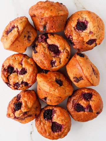 Banana blackberry muffins on a plate on a table top and side view.