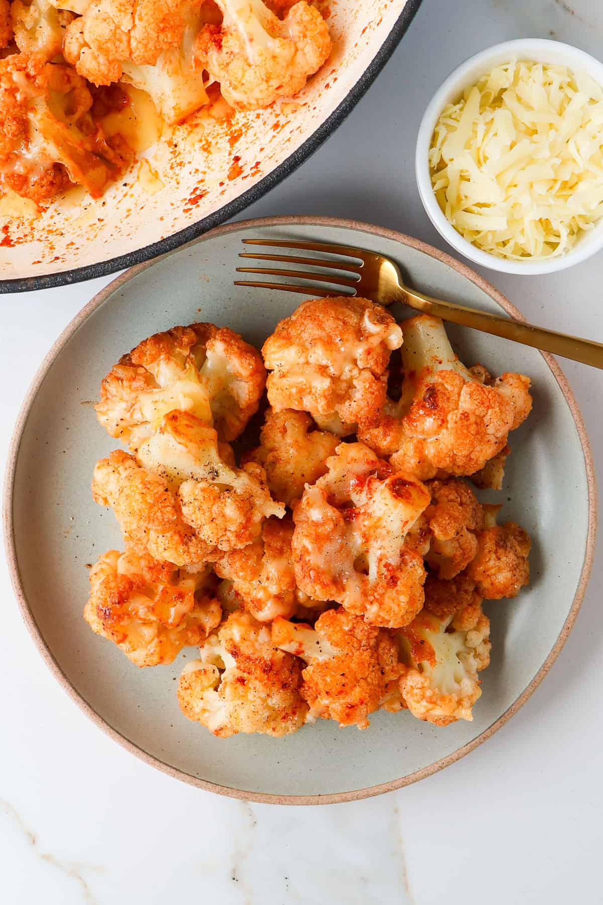 Cheesy cauliflower on a plate with a fork.