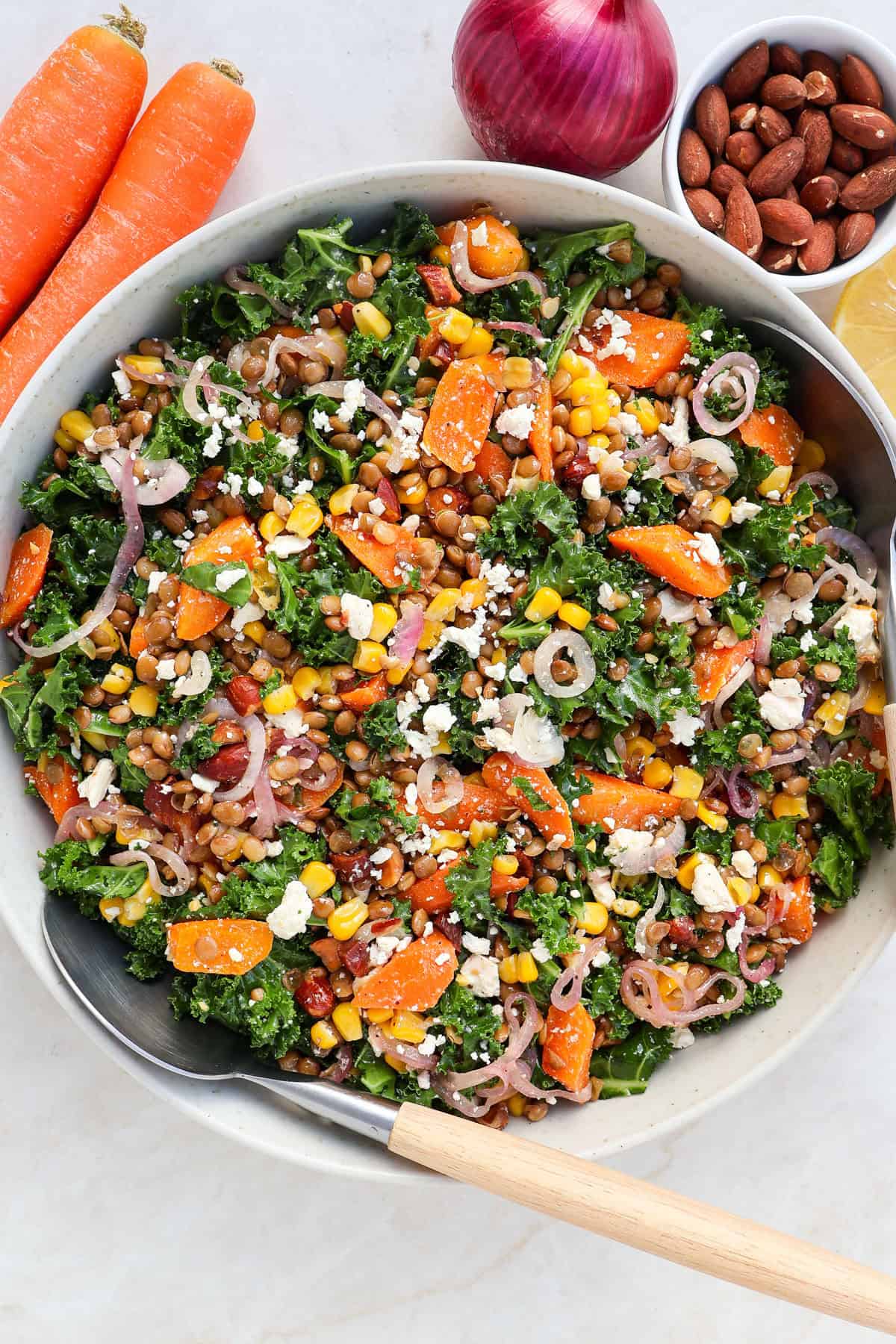 Kale and lentil salad in a bowl with wooden spoons.