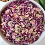 Red cabbage salad in a bowl with tongs.