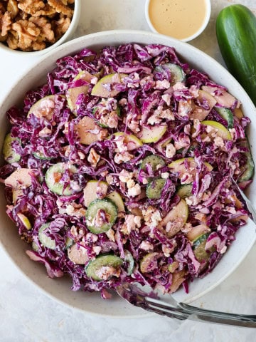 Red cabbage salad in a bowl with tongs.