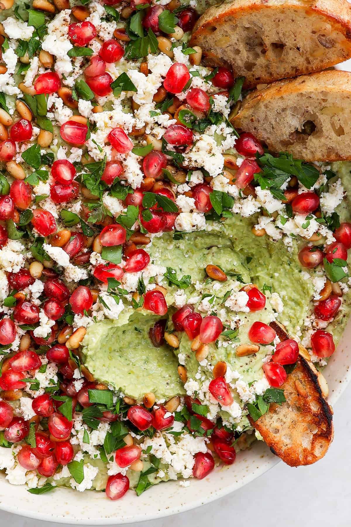 Close up shot of the pea dip scooped up with crostini bread to see inside.