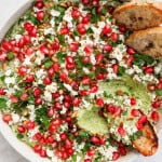 Green pea dip garnished and scooped up with crostini bread to see inside.