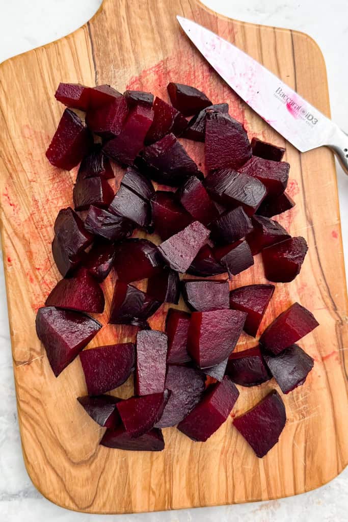 Roasted beetroots chopped up on a cutting board.