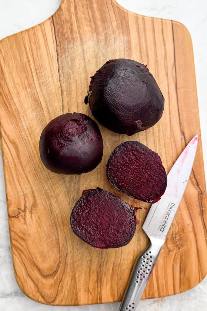 Roasted beetroots sliced in half on a cutting board.