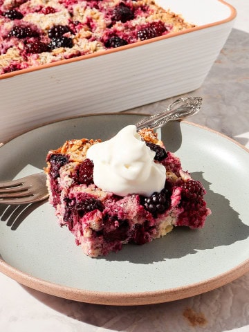 Side shot of the blackberry baked oatmeal served on a plate topped with yoghurt.