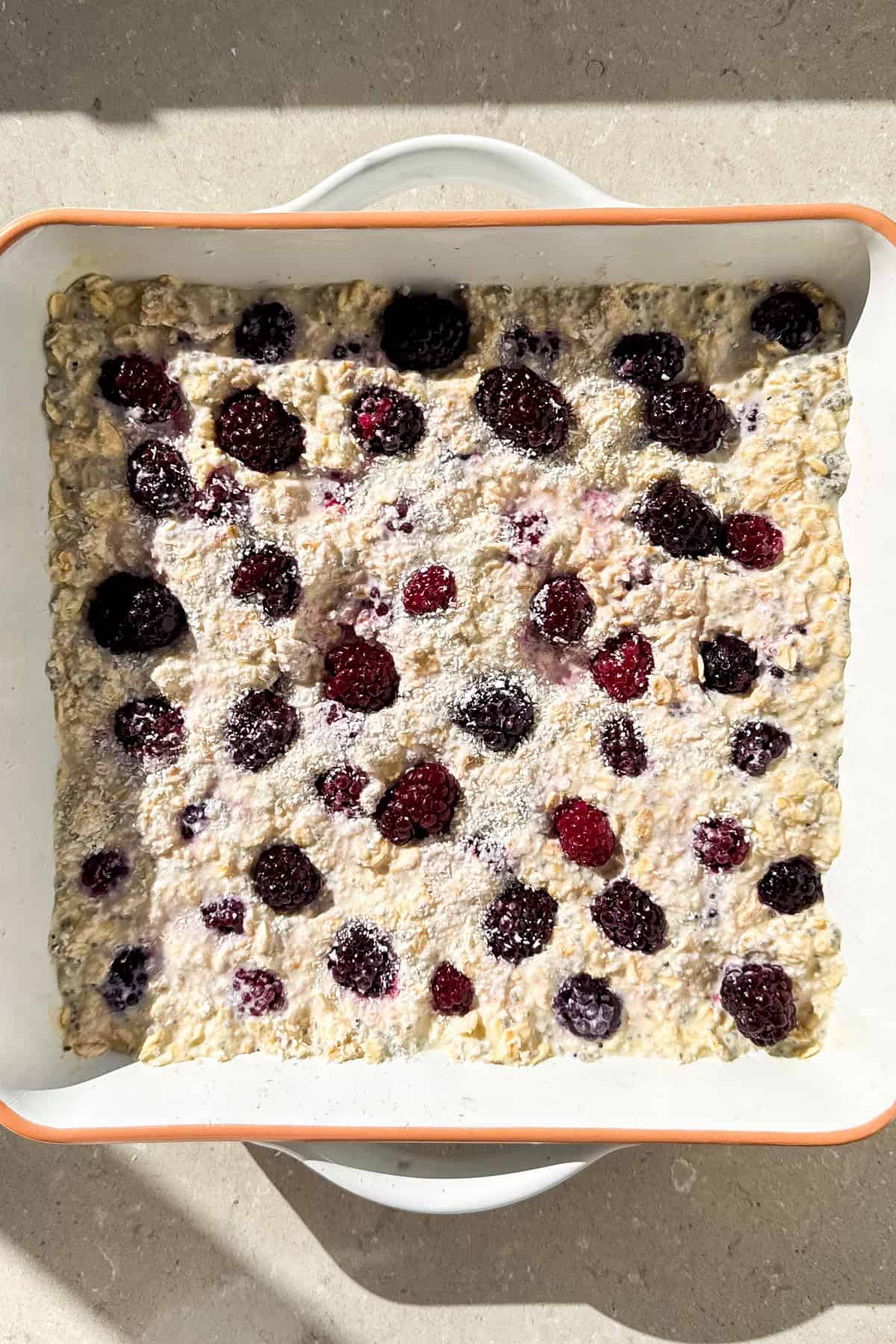 Top view of the blackberry oatmeal sprinkled with coconut before being baking.
