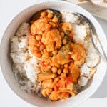 Chicken and chickpea curry served over rice in a bowl.