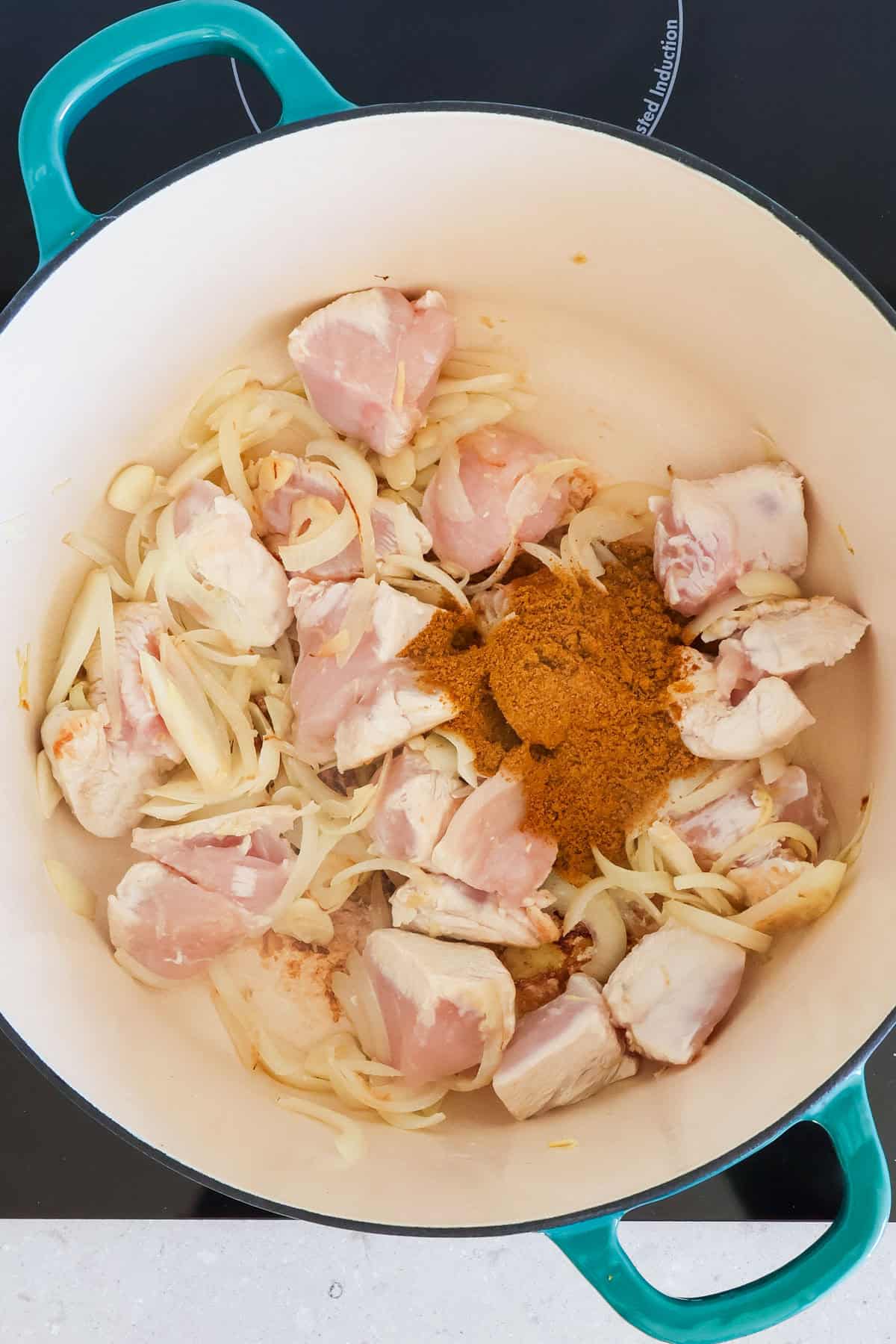 Chicken getting browned off and curry powder added.