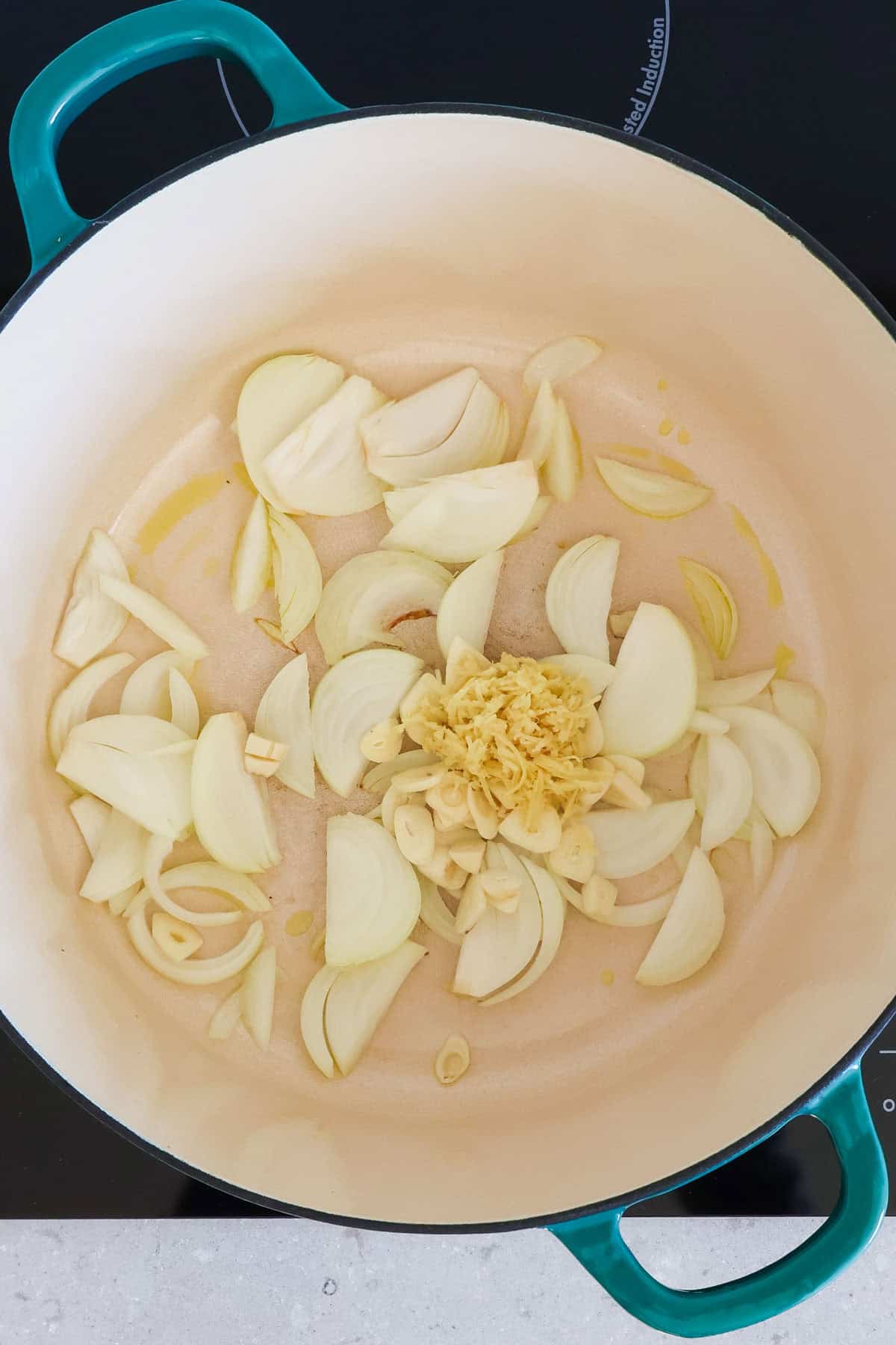 Onions, garlic and ginger being sautéed in a pot.