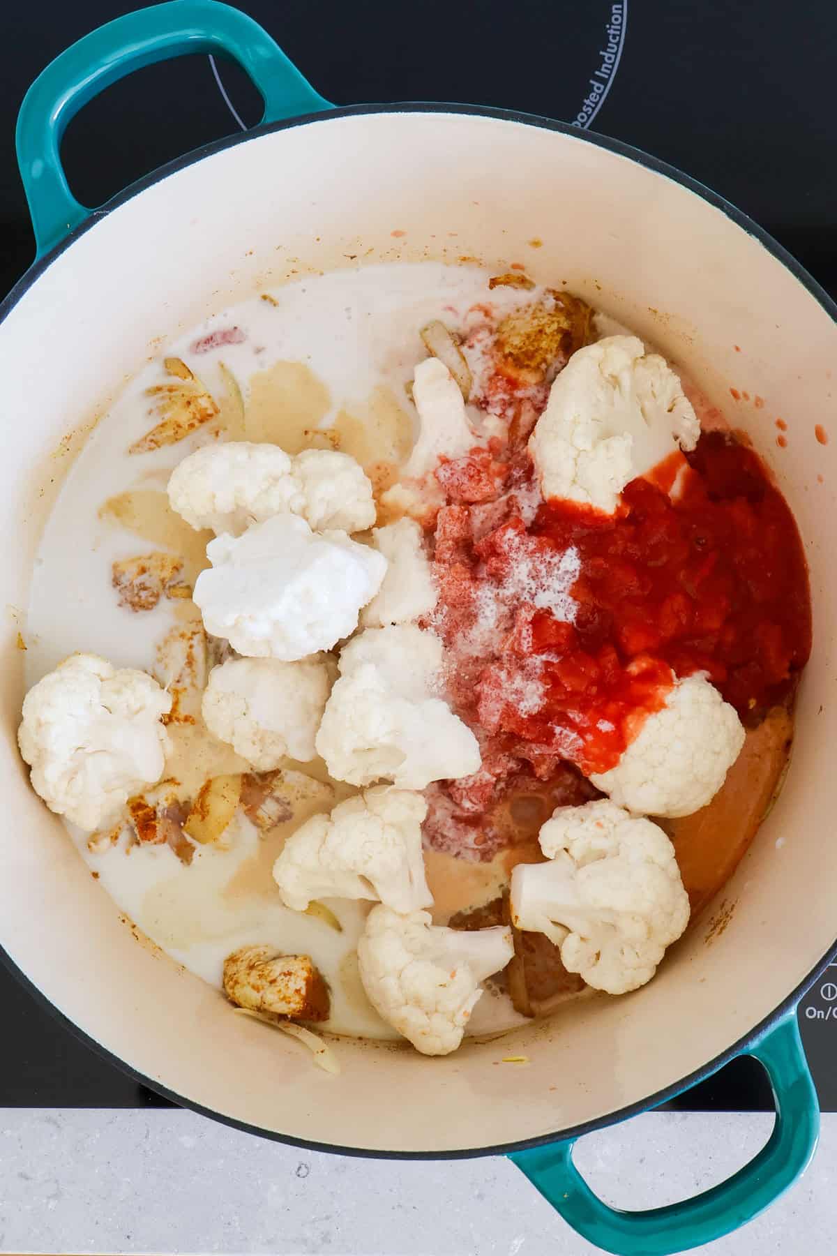 Cauliflower florets, coconut milk and canned tomatoes added to the pot.