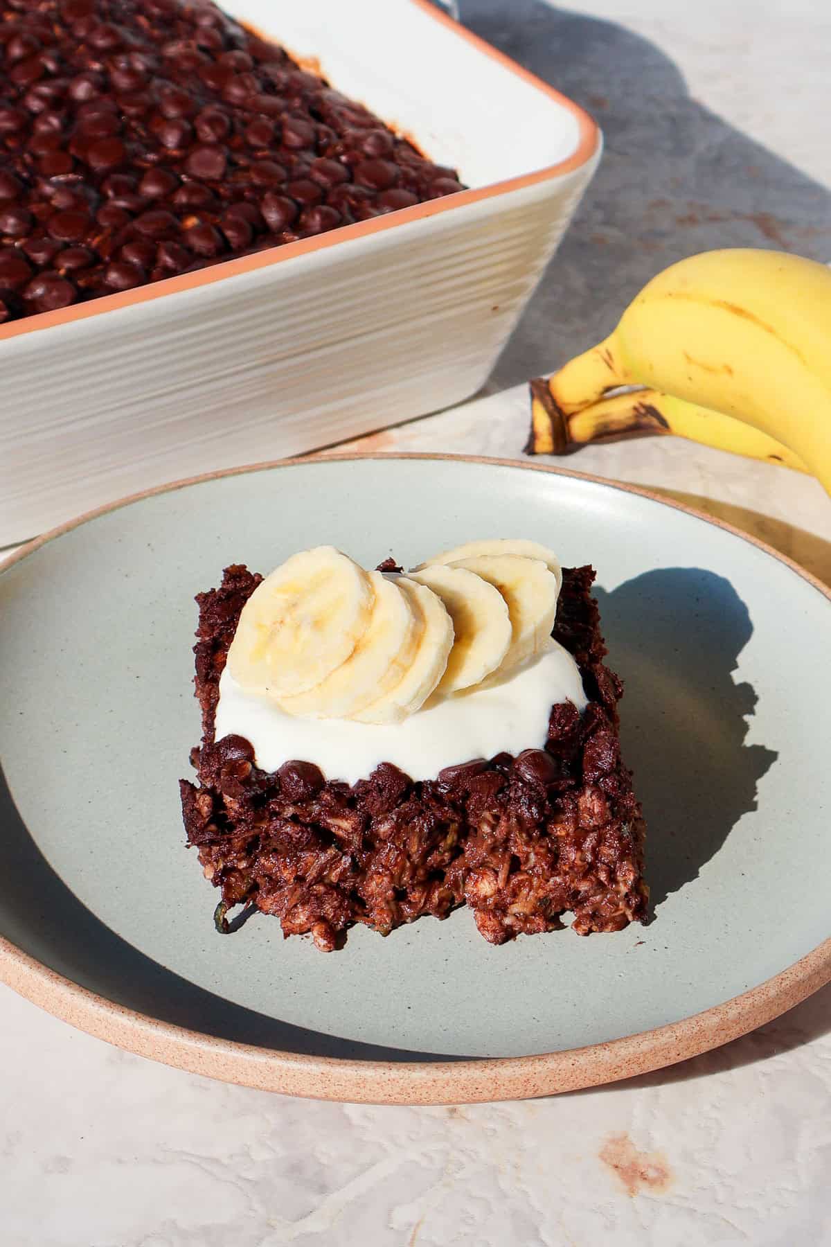 Side shot of the chocolate baked oatmeal on a plate topped with yoghurt and banana.