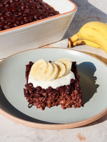 Side shot of the chocolate baked oatmeal on a plate topped with yoghurt and banana.